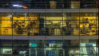 Glowing windows in multistory modern glass and metal office building light up at night timelapse [upl. by Anieral]